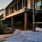 Extension maison sur pilotis au-dessus d’une pente, terrasse sur pilotis